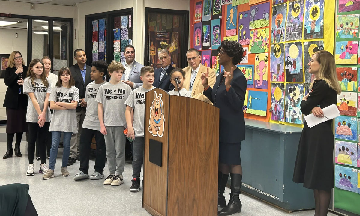 This is a photo of Education Commissioner Charlene Russell-Tucker speaking at a podium with a group of children next to her.